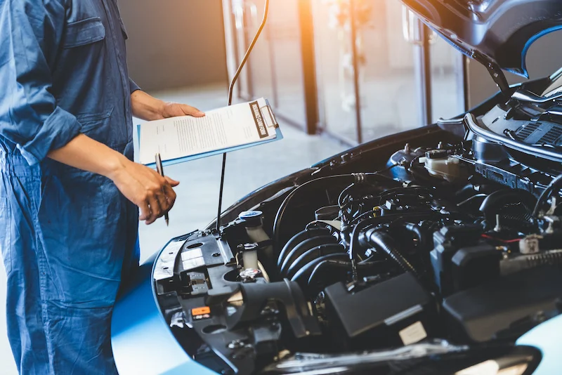 Man holding clipboard inspecting engine bay